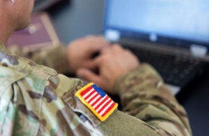 Military man with U.S. flag patch on soldier working on laptop computer