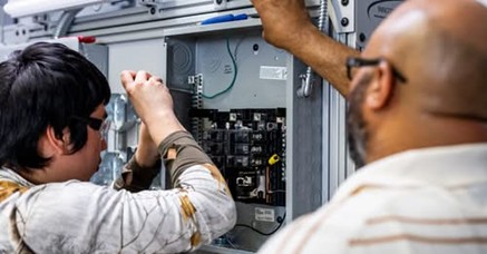 Image of two people attending to a circuit board