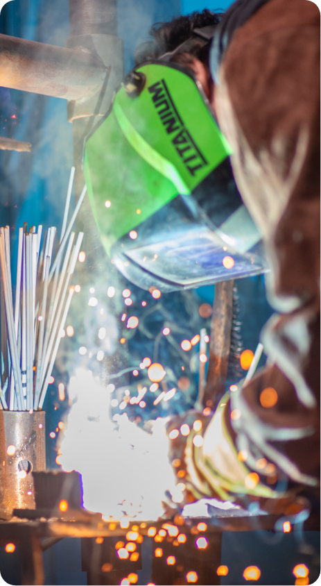A person wearing safety gear and using a welder.