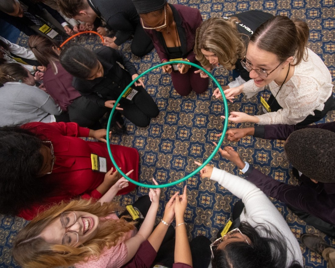 students in a circle holding a hoolu hoop