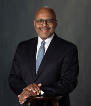 Jones Maurice Professional portrait of Maurice Jones wearing a suit and glasses.