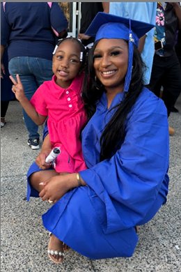 Tiana Randolph in her graduation cap and gown, smiling with her young daughter